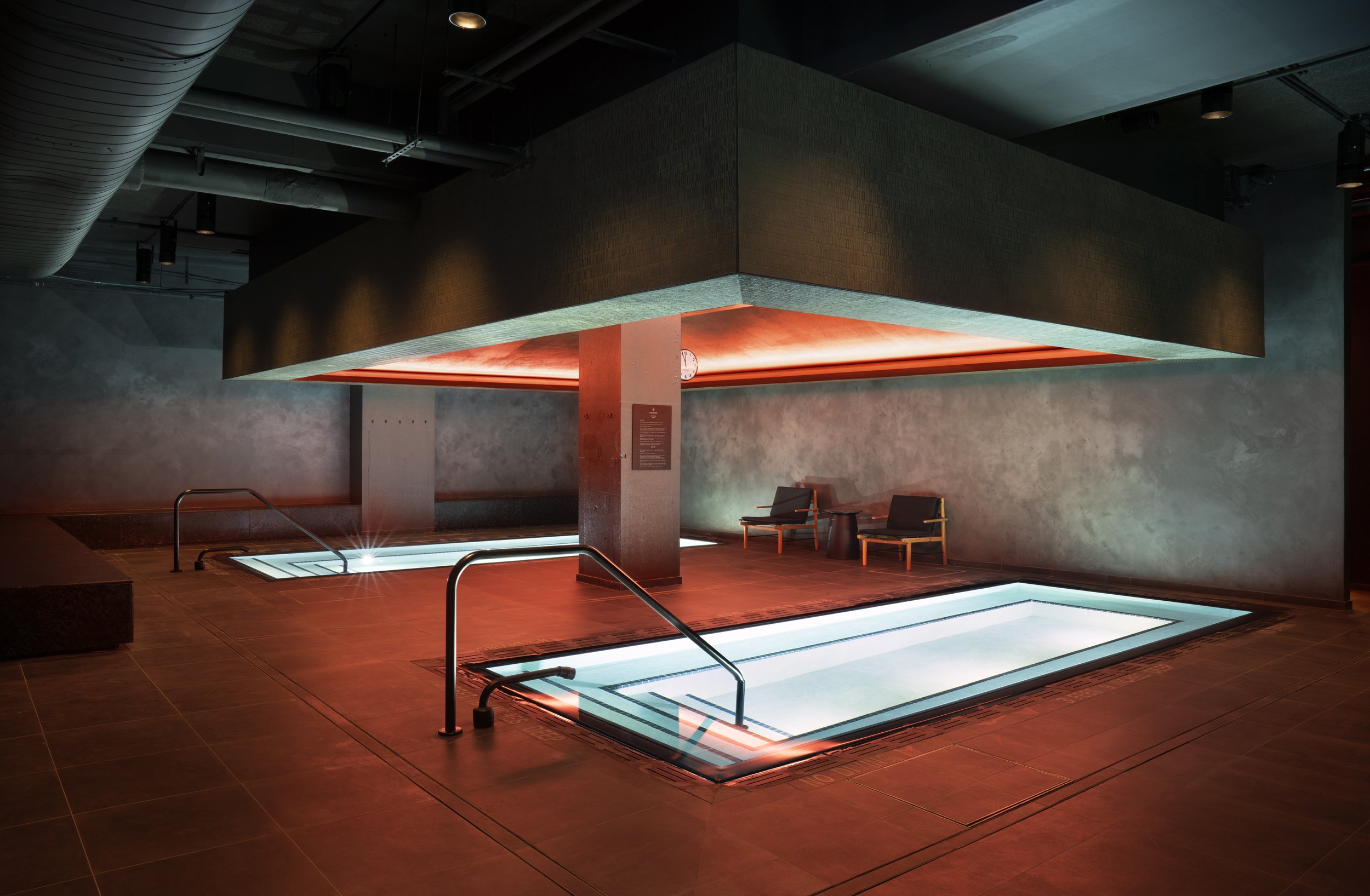 Bathhouse spa interior with plunge pools under an amber-lit ceiling
