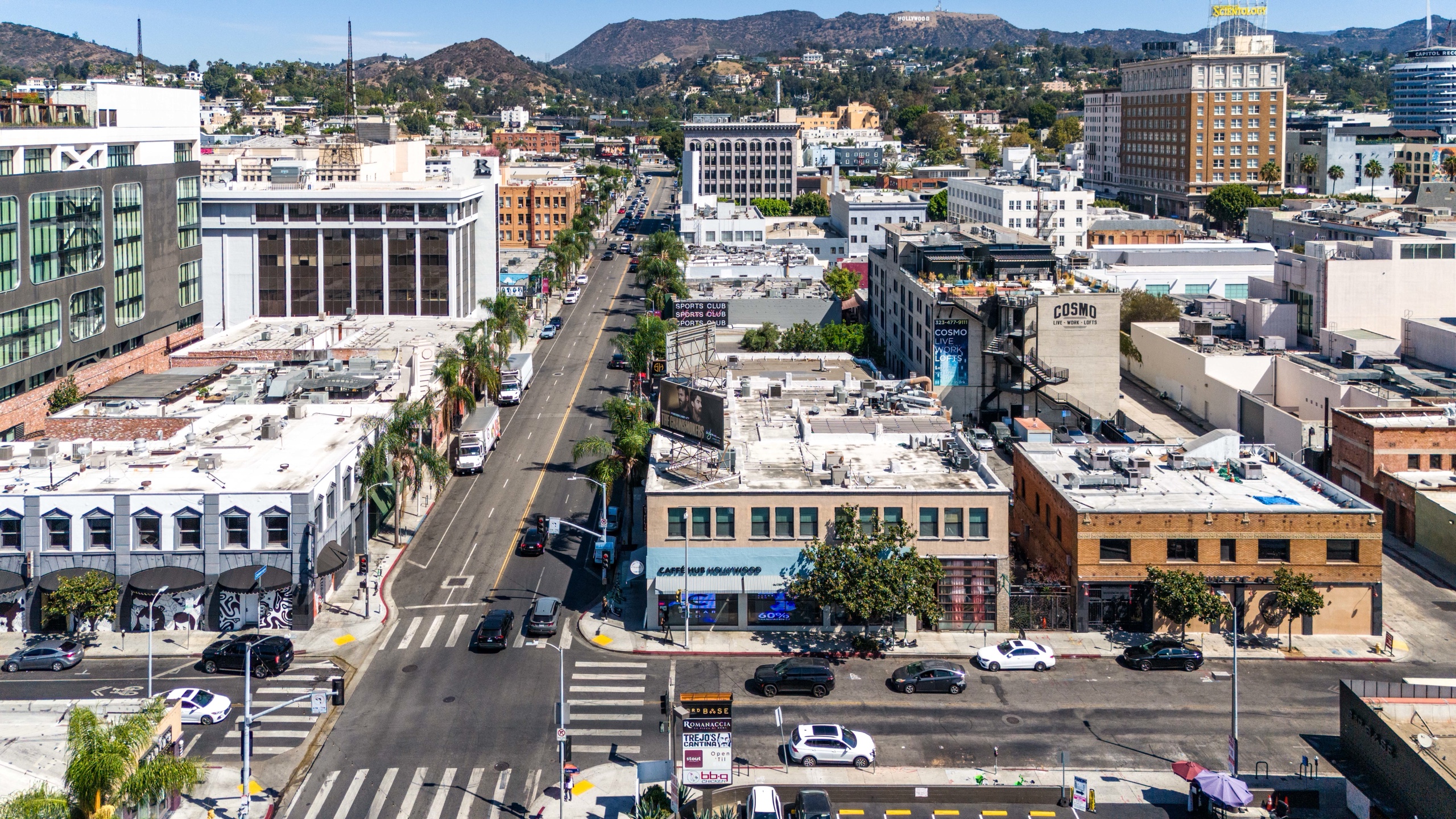Aerial view north along Cahuenga Boulevard with the subject corner in the foreground and the Hollywood Sign beyond