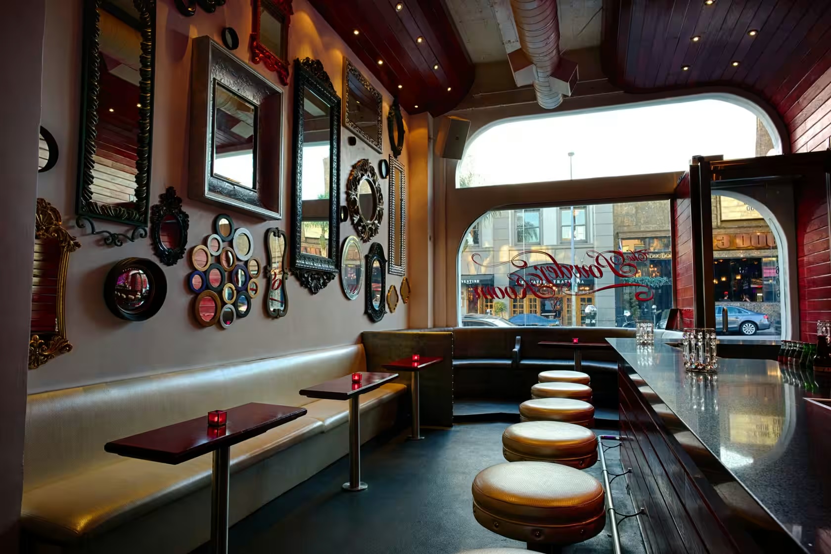 Bar interior at 1602–1608 N Cahuenga: mirrored gallery wall, leather banquettes and window seating over the boulevard
